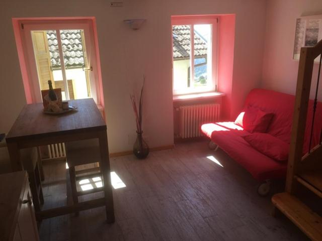 拉瓦罗内Appartamento Dalma Foresta的一间带红色沙发和两扇窗户的客厅