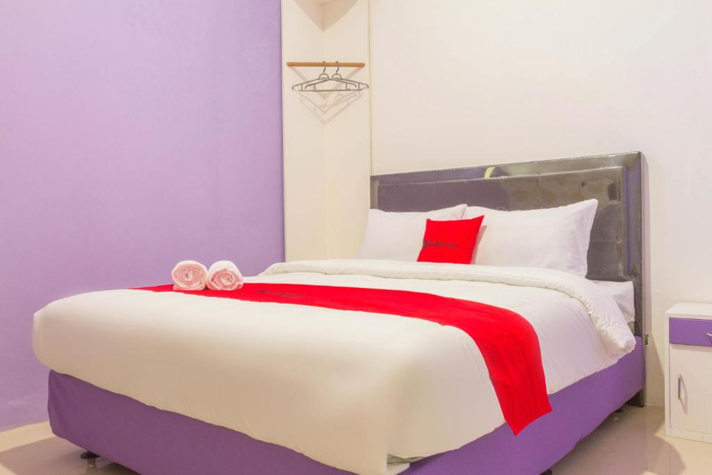 井里汶RedDoorz Plus @ Tuparev Cirebon 2的卧室配有带红色枕头的大型白色床