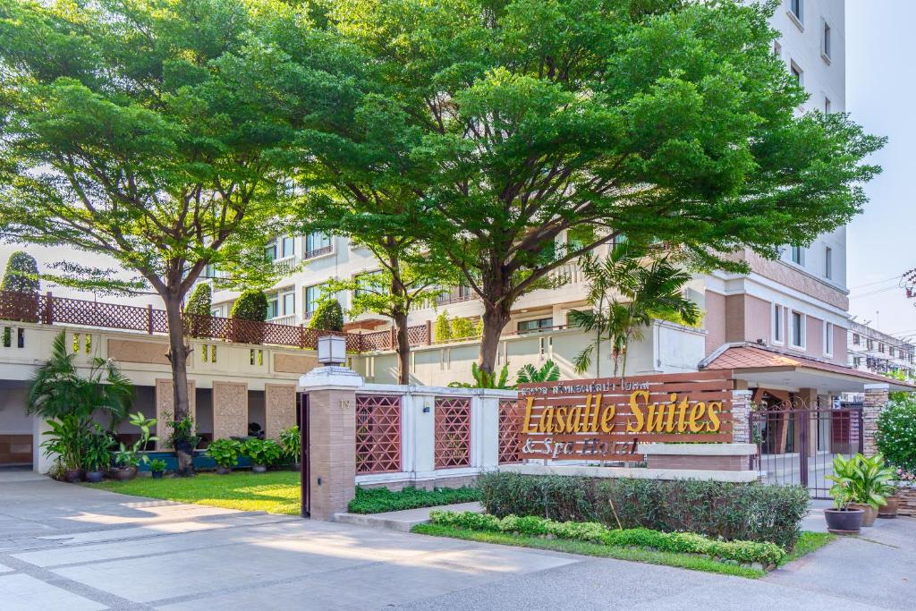 曼谷Lasalle Suites Hotel & Residence的树木丛生的建筑前的标志