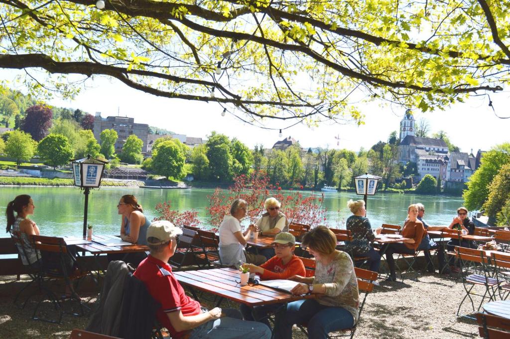 劳芬堡Alte Post - Hotel Am Rhein-Ufer Laufenburg的一群坐在湖边桌子旁的人
