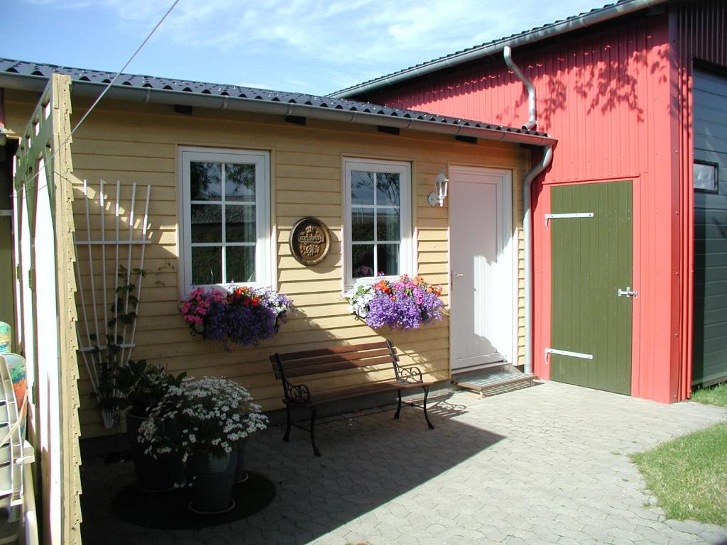 VojensBed and Breakfast Nustrup的红色的房子,设有两扇窗户和天井上的长凳