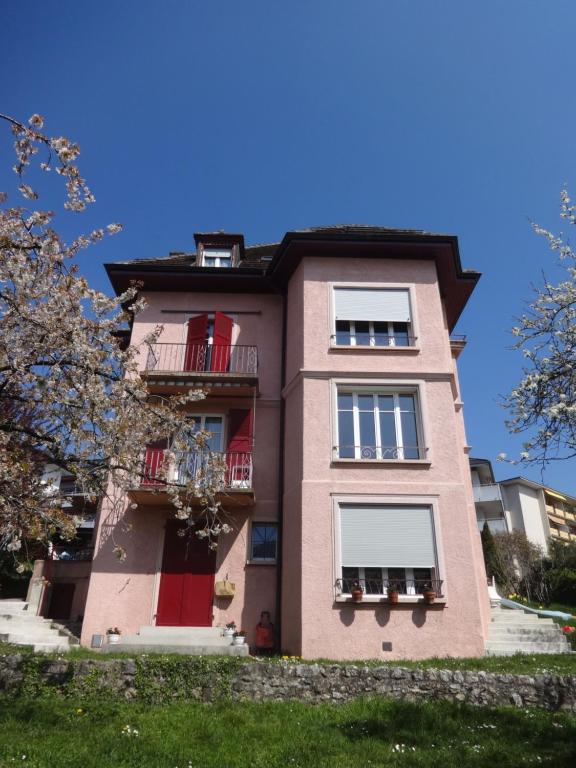 PrillyChambres meublées Prilly - Lausanne的粉红色的建筑,有红色的门窗