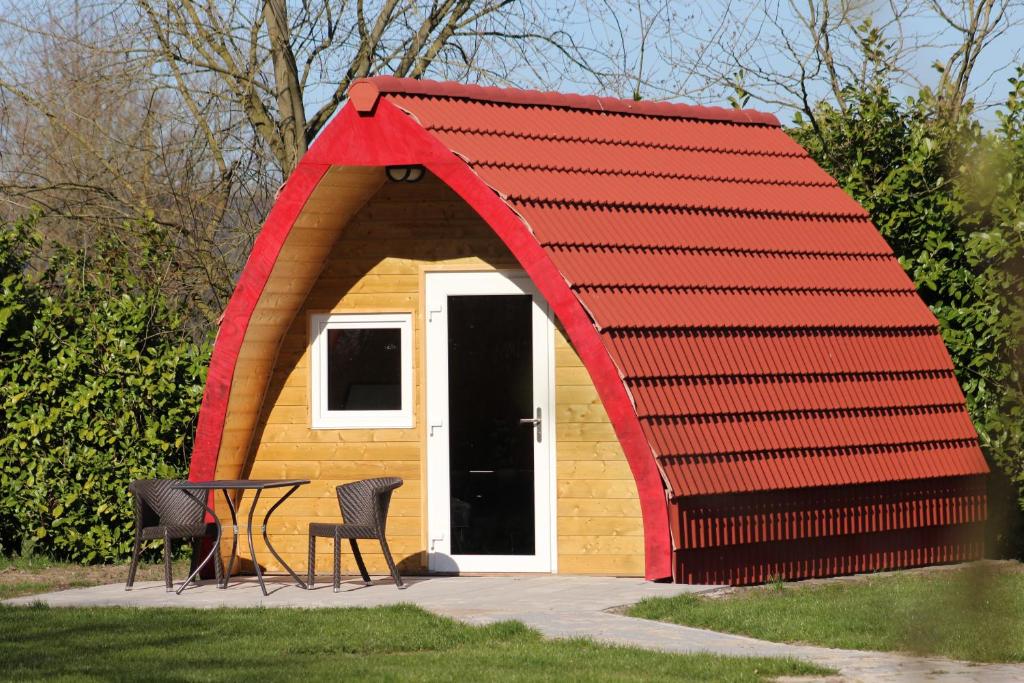 DrijberLuxe Eco Pod op Camping de Stal的红色屋顶棚屋,配有两把椅子和一张桌子