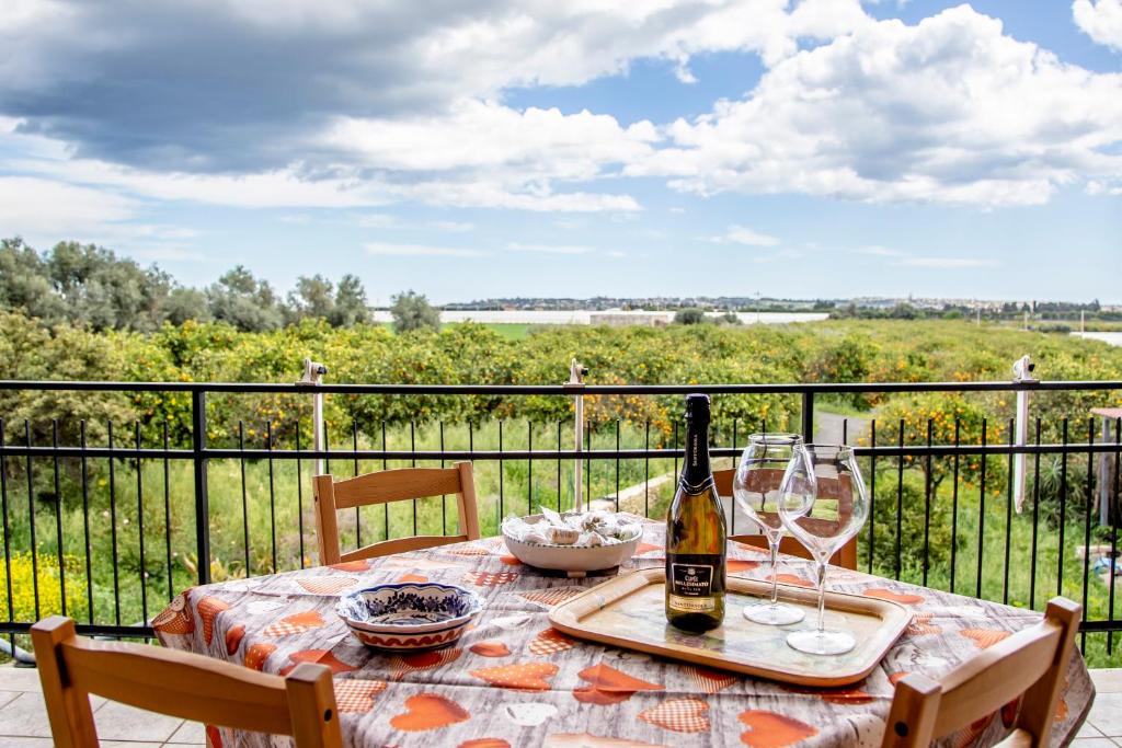 锡拉库扎Casa Abela的阳台上的桌子上摆放着一瓶葡萄酒和玻璃杯