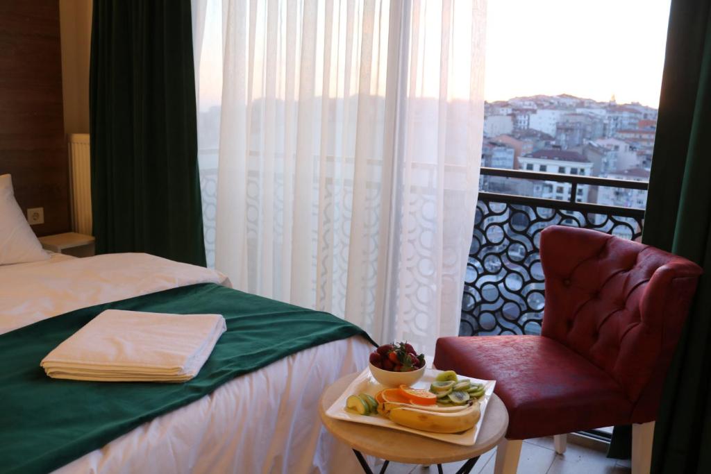 伊斯坦布尔Musk Hotel的一间酒店客房,配有一张床和一把椅子,并配以托盘食物