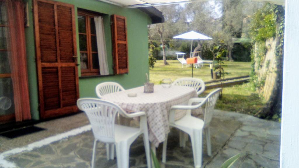 圣玛格丽塔-利古雷Lo Chalet tra gli ulivi的庭院内一张带白色椅子和遮阳伞的桌子