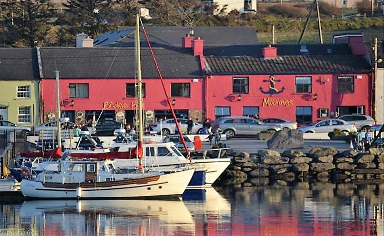 波特马吉The Moorings Hotel & Seafood Restaurant的两艘船停靠在码头,有一座红色的建筑