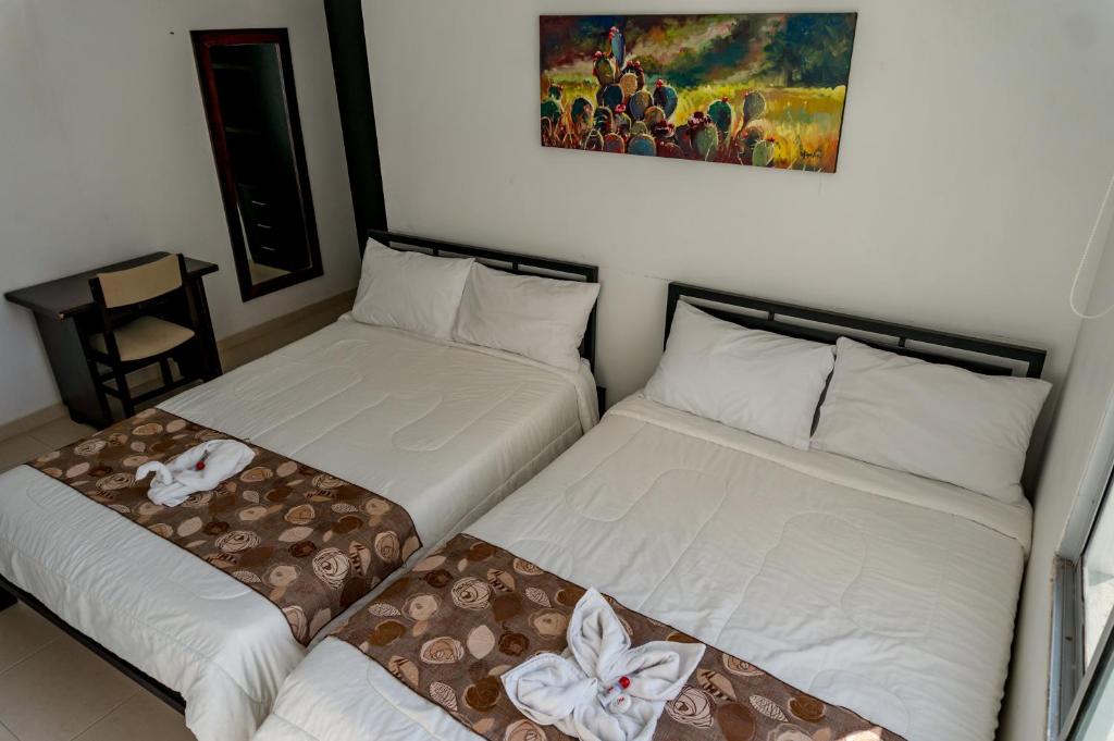 San Juan del Cesar萨拉约酒店的两张睡床彼此相邻,位于一个房间里