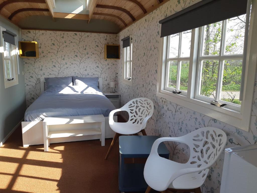 MeddooB&B Pipowagen "de Luxe" op Wellness Camping en B&B的一间卧室配有一张床和两把白色椅子