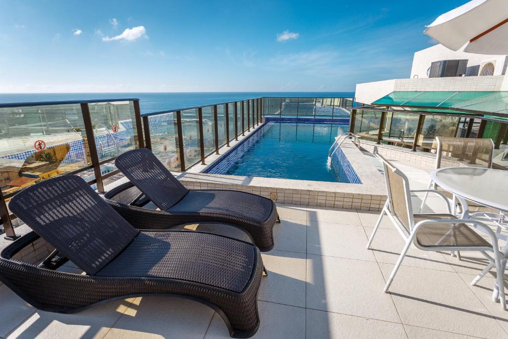 萨尔瓦多Rede Andrade Riviera Premium的一个带两把椅子的阳台和一个游泳池
