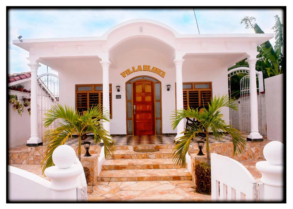 CaibariénHostal "Villa Blanca"的一间红色门的白色房子