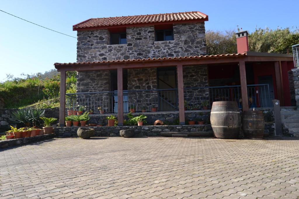 莫尼兹港Recantos do Castanheiro的一座石头房子,带门廊和桶