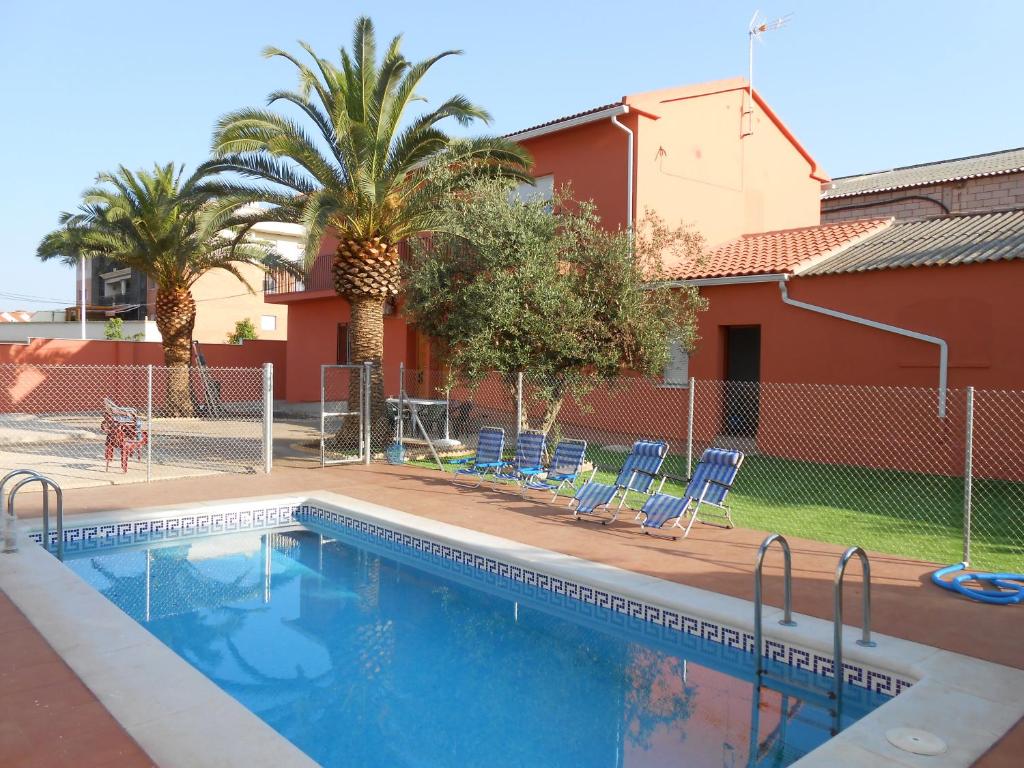 梅里达多莫斯阿垮旅游公寓的一个带蓝色椅子的游泳池,棕榈树