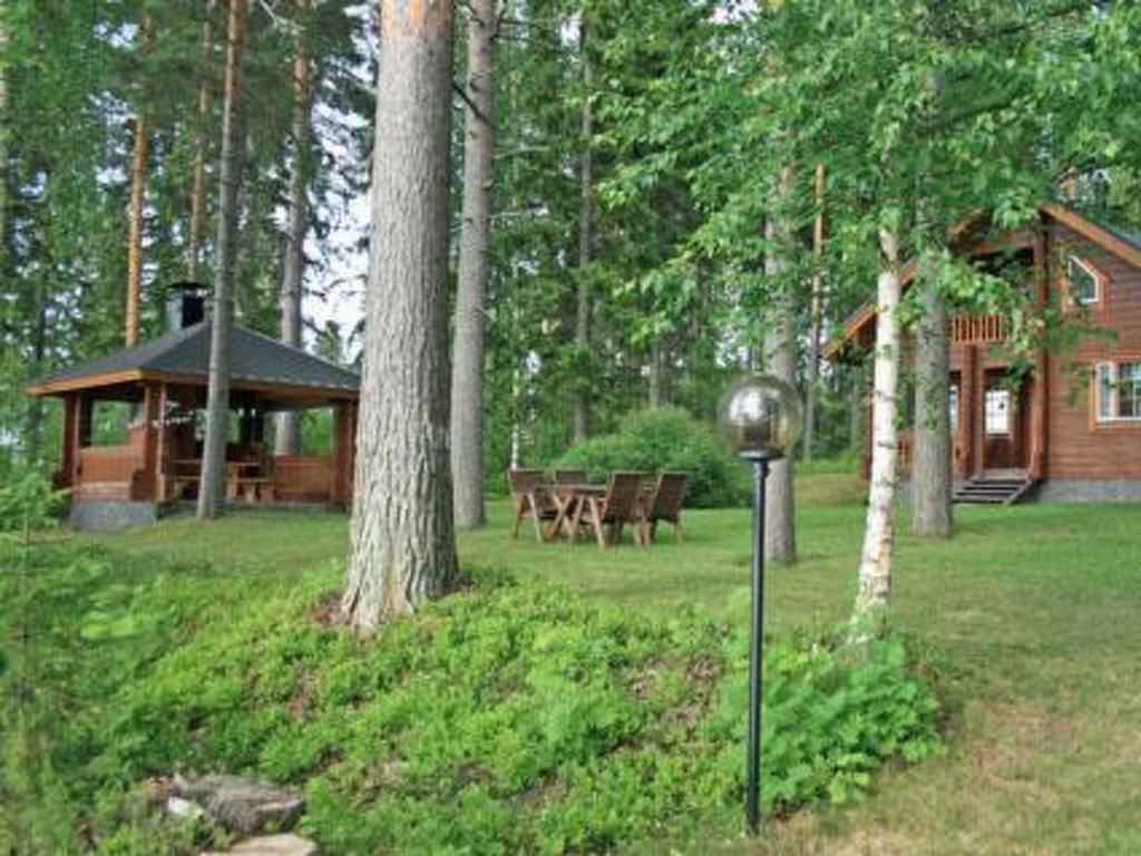 AhvionniemiHoliday Home Korvenvalkama by Interhome的树林中的小屋,院子里有时钟