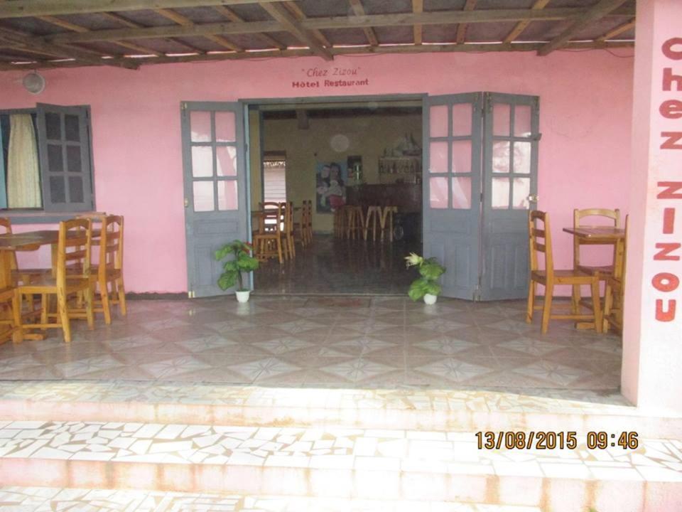 ManakaraChez Zizou Manakara的粉红色的建筑,配有椅子和桌子,还有门