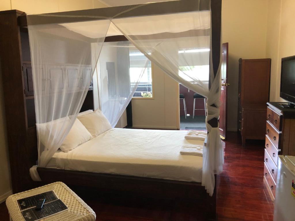 普拉瑟潘威尔斯王子酒店的一间卧室配有一张天蓬床和一台电视机