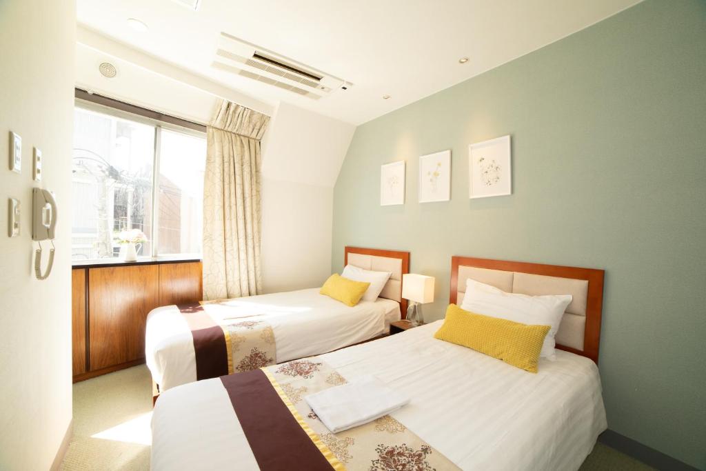东京Tabata Oji Hotel的一间卧室设有两张床和窗户。