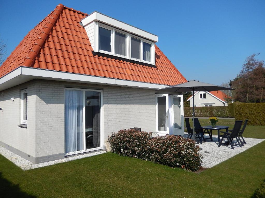 诺德克豪特Holiday Home de Witte Raaf-3 by Interhome的一座带桌子和雨伞的橙色屋顶的房子