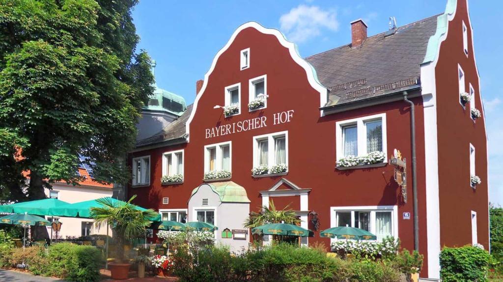 瓦尔德萨森Hotel Bayerischer Hof的一座红色的建筑,上面有小贩宾馆的标志