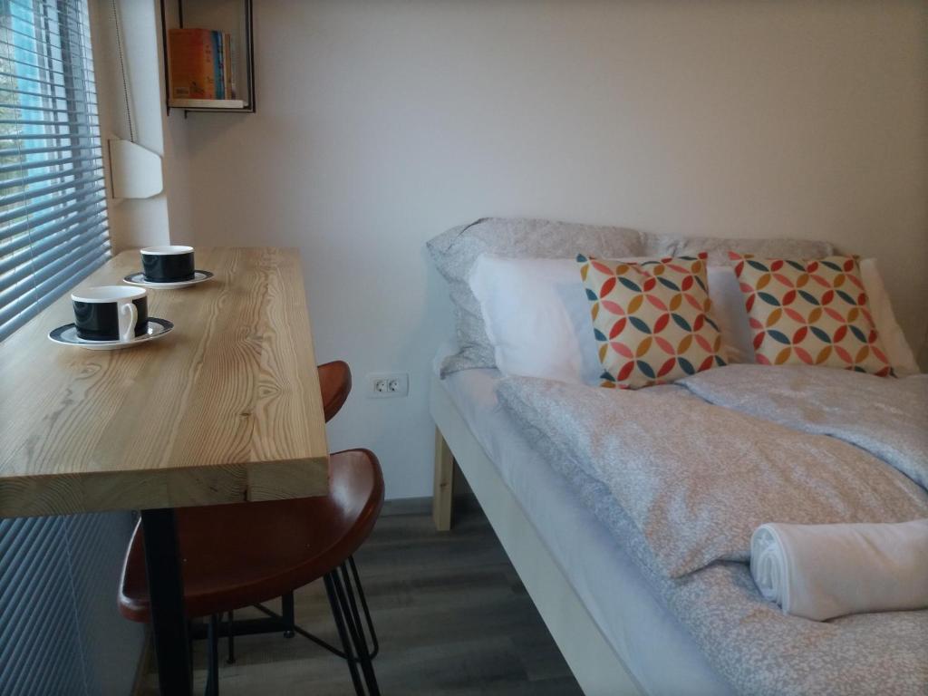 卡姆尼克Mamut Stay的一间设有床铺和一张木桌及两个咖啡杯的房间