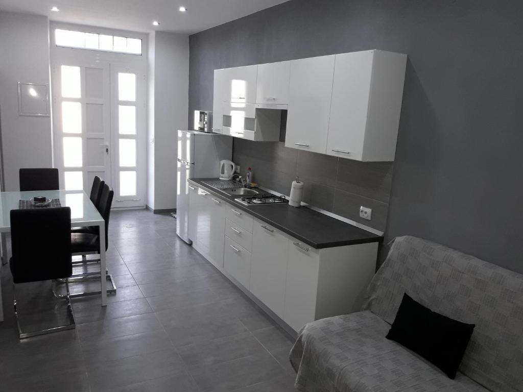 木洛希尼Apartments Vidulić的厨房配有白色橱柜、桌子和沙发