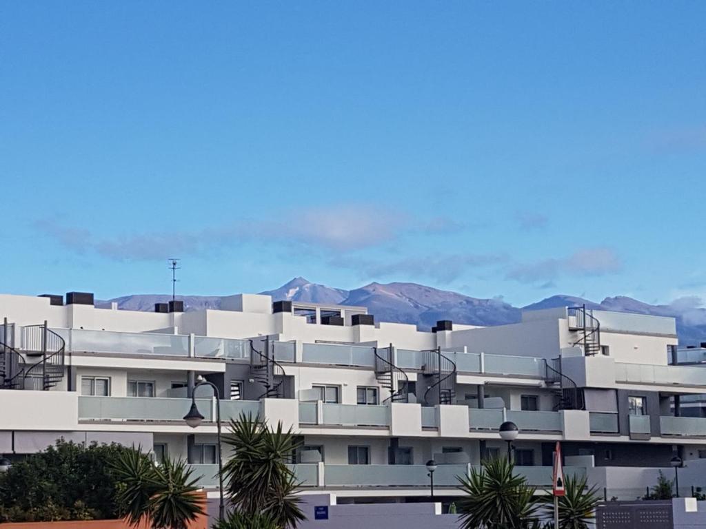 厄尔梅达诺Vista Montaña Roja Medano的白色公寓大楼,背景为山脉