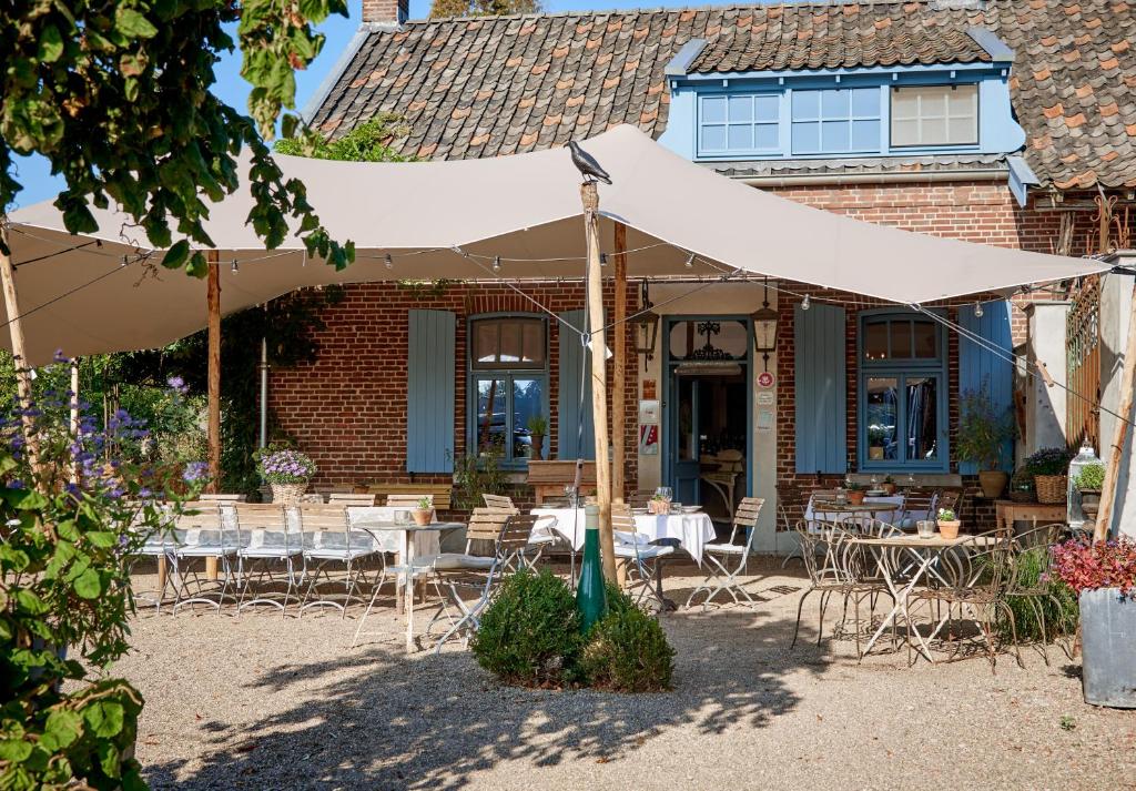 塞弗讷姆Gasterie Lieve Hemel的一个带桌椅的白色遮阳伞下庭院