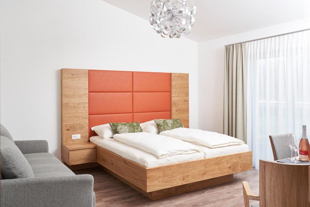AngernWeinhof - Gästehaus Maier的一间卧室配有一张床、一张沙发和一把椅子