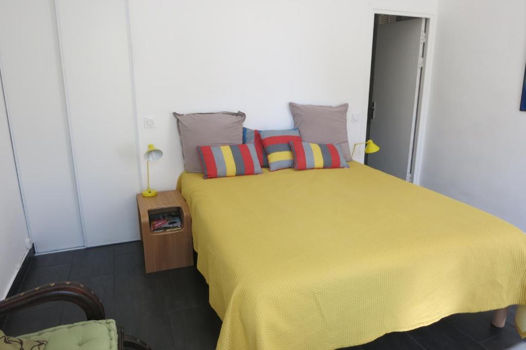 滨海拉塞讷Villa les Lys的一间卧室配有黄色的床和色彩缤纷的枕头