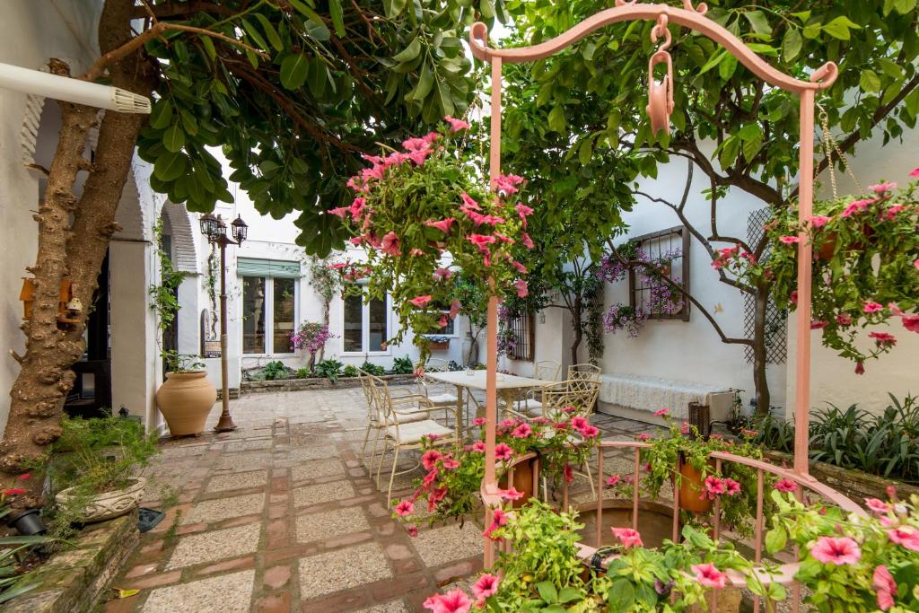 科尔多瓦Patio Márquez的庭院里种有粉红色的鲜花,配有桌椅