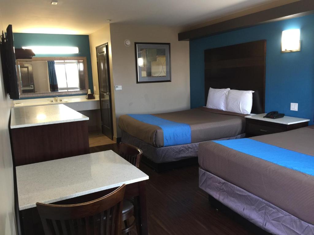 MaywoodCrystal Palace Inn的酒店客房设有两张床和一张桌子。