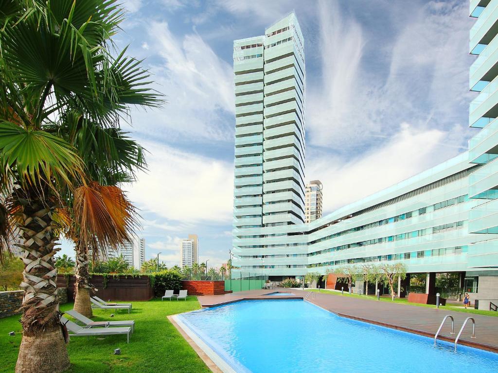 巴塞罗那巴塞罗那加西亚法利亚大道公寓的一座高大的建筑,在一座建筑前设有一个游泳池