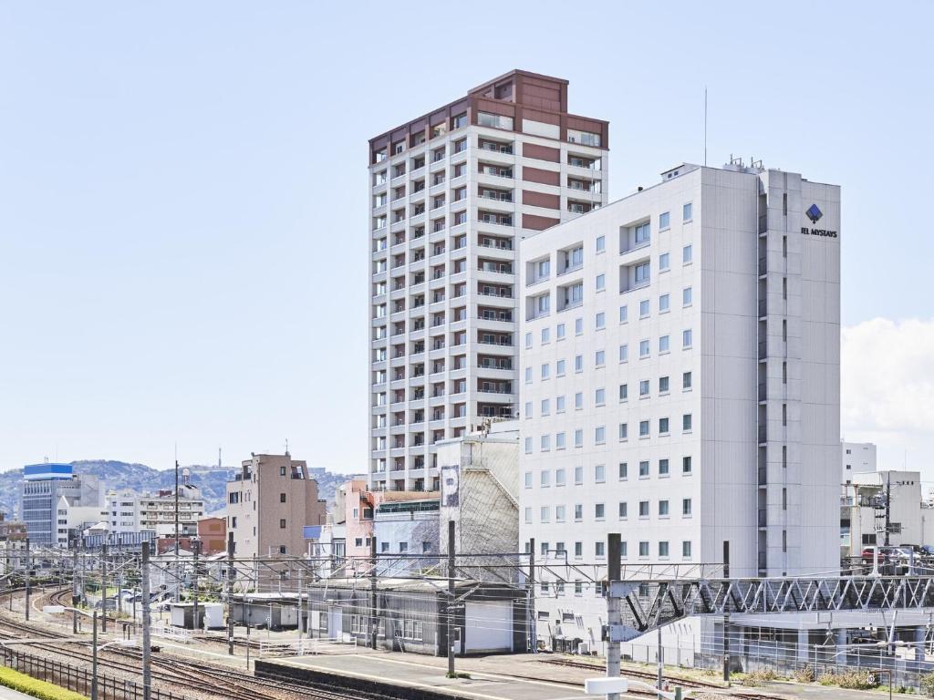 静冈HOTEL MYSTAYS Shimizu的火车站旁的一座高大的白色建筑