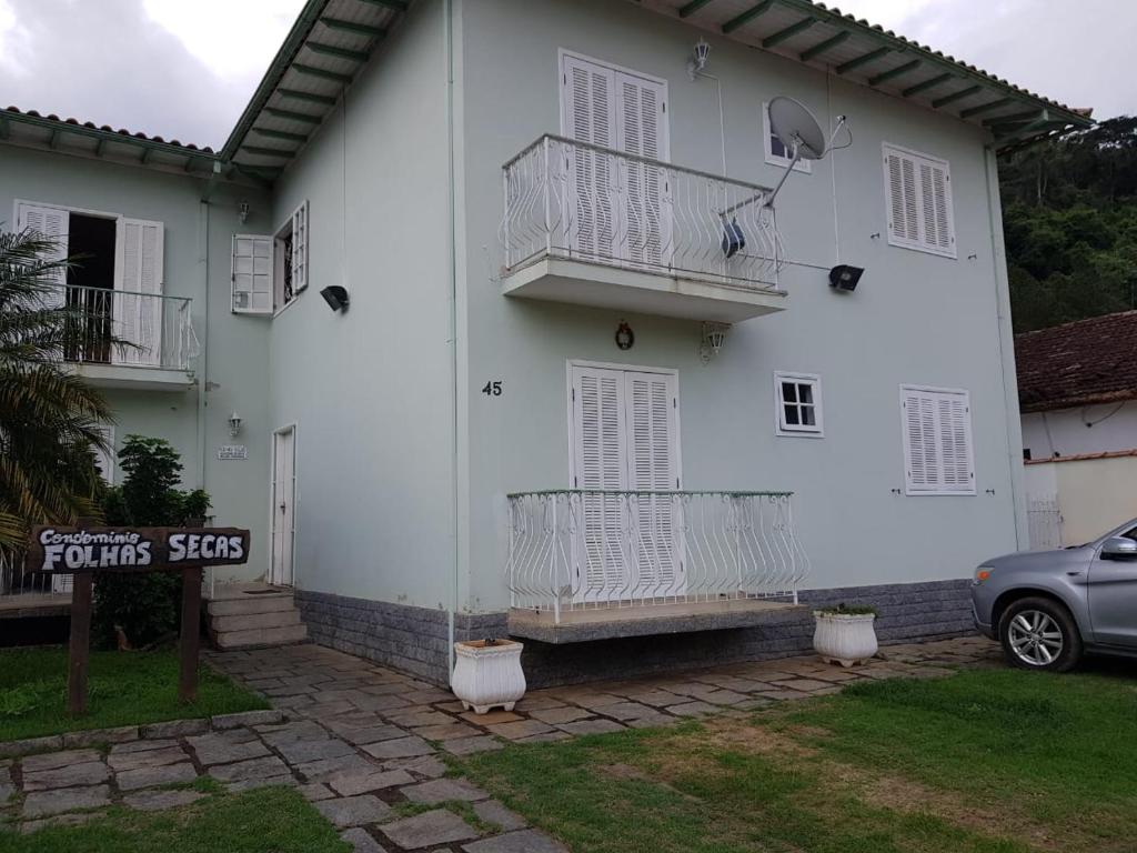 康赛瓦托利亚Condominio Folhas Secas的带阳台和汽车的白色房屋