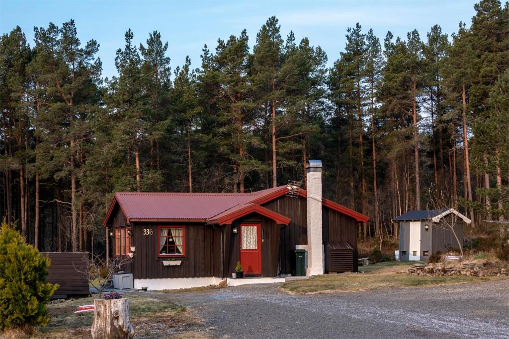 LyngstadIverhjelen Near Atlantic Road的树林中的一个红色屋顶的小小屋