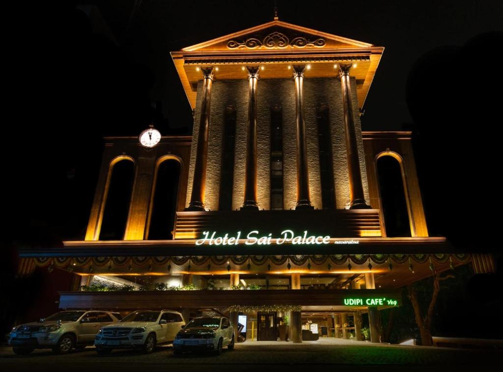 门格洛尔Hotel Sai Palace , Mangalore的一座建筑,前方设有钟楼,汽车停泊在钟楼