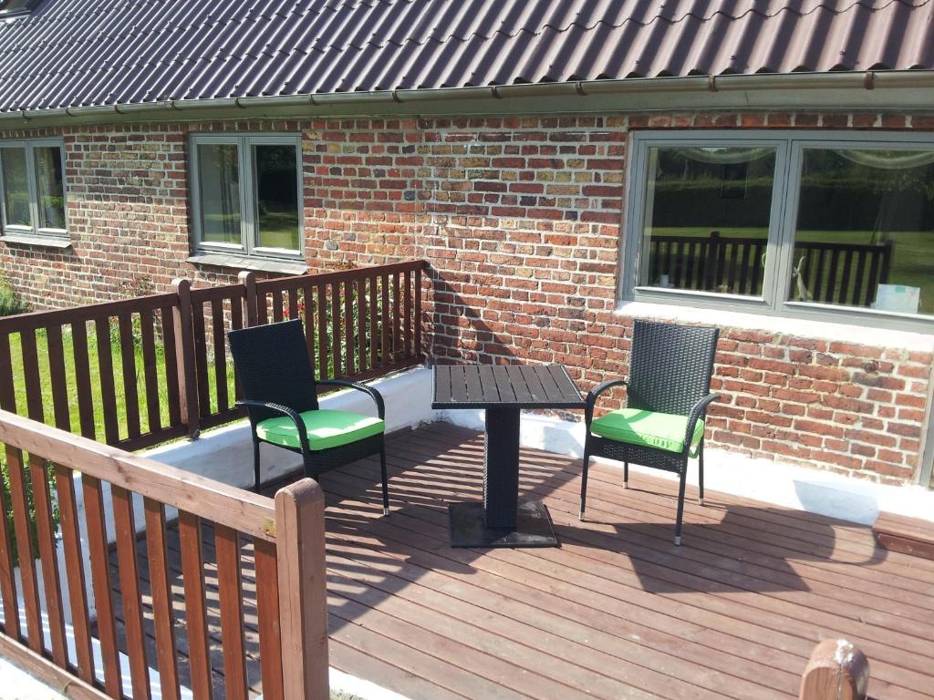 灵克宾Lilleledgaard Apartment的木制甲板配有两把椅子和一张桌子