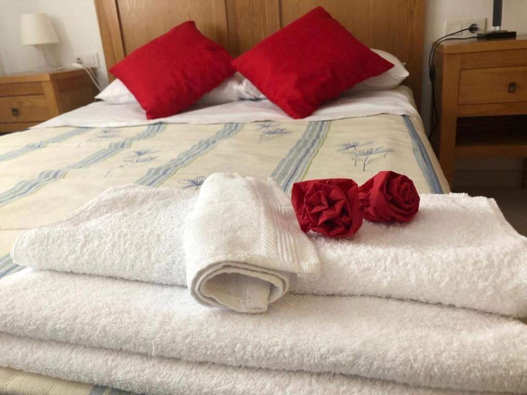 托雷德尔马尔Apartamento MILA的一张带白色毛巾和红色枕头的床