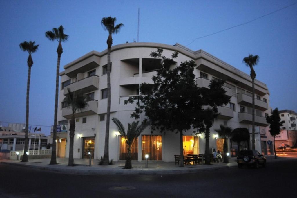 拉纳卡艾利索酒店的一座白色的大建筑,前面有棕榈树