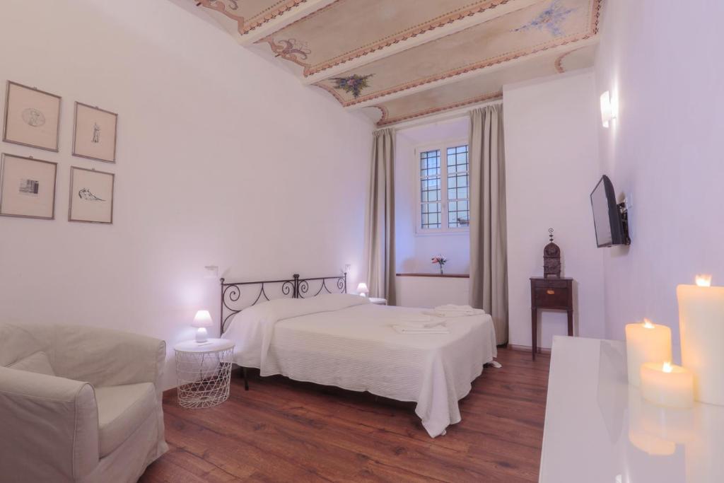 卢卡San Pierino Charming Rooms的白色卧室配有一张床、一张沙发和蜡烛
