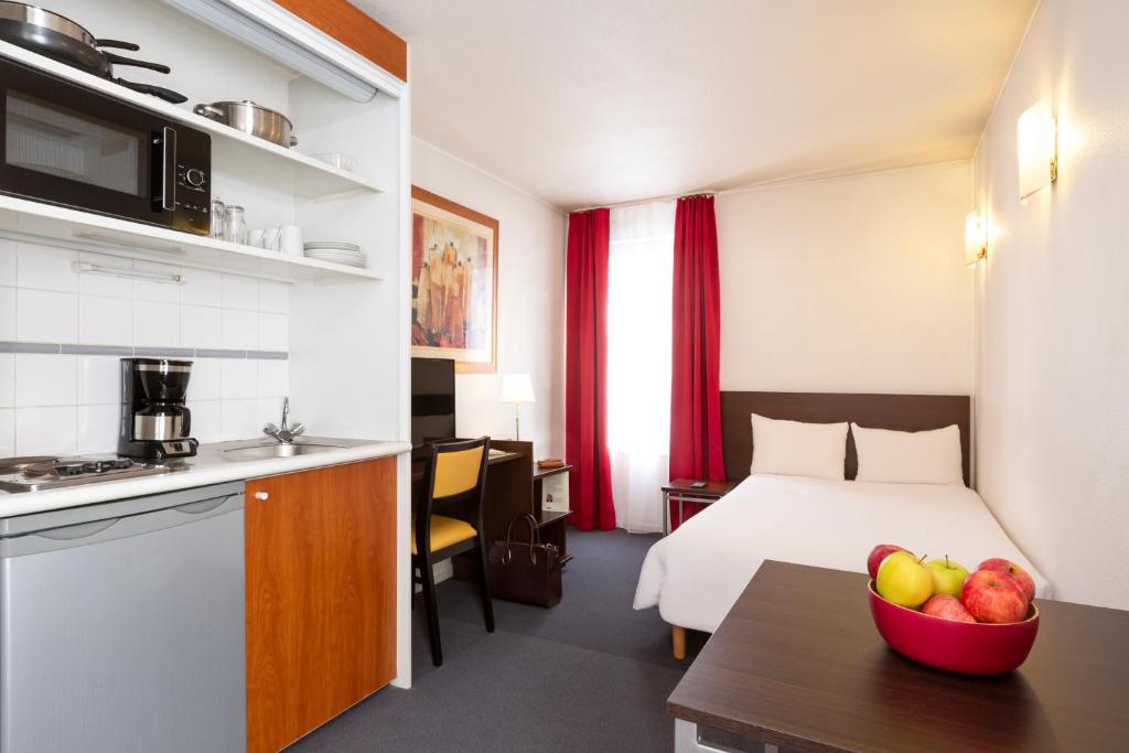 库尔布瓦拉德芳斯爱达格公寓式酒店 - 莱昂纳尔达芬奇的酒店客房,配有一张床和一碗水果放在桌子上