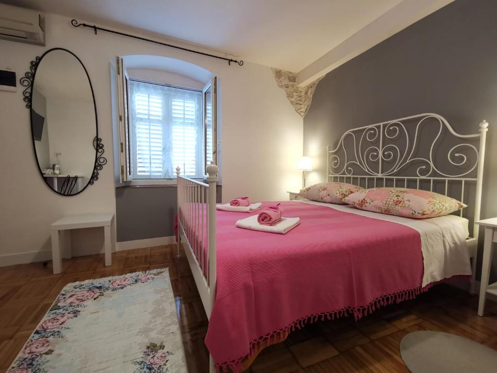 斯普利特Palace Inn Rooms的一间卧室配有一张带粉色毯子和镜子的床