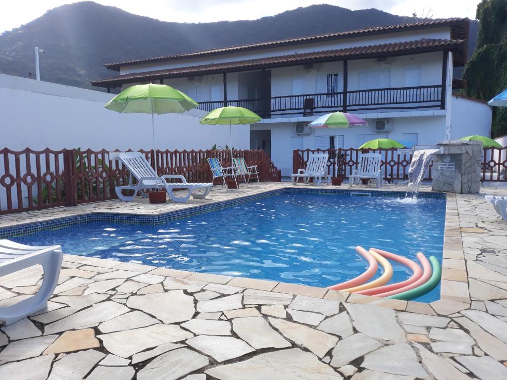马利西亚斯POUSADA TANI COM AR E PISCINA em MARESIAS的房屋旁的游泳池配有椅子和遮阳伞