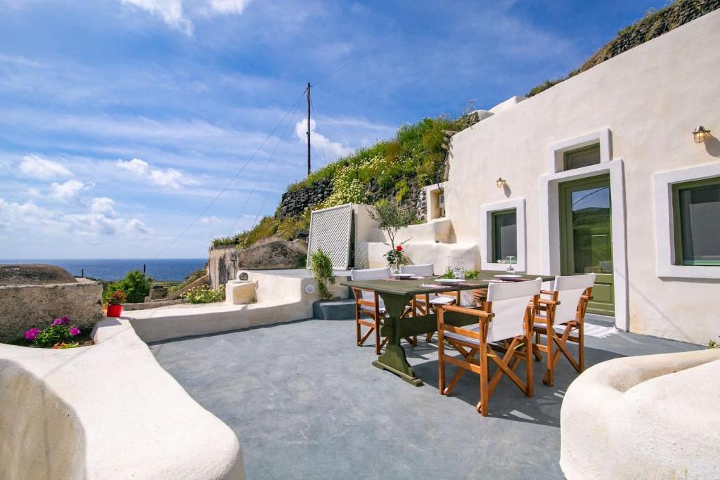 锡拉夏岛Agrilia secluded cave house的一个带桌椅的庭院和大海