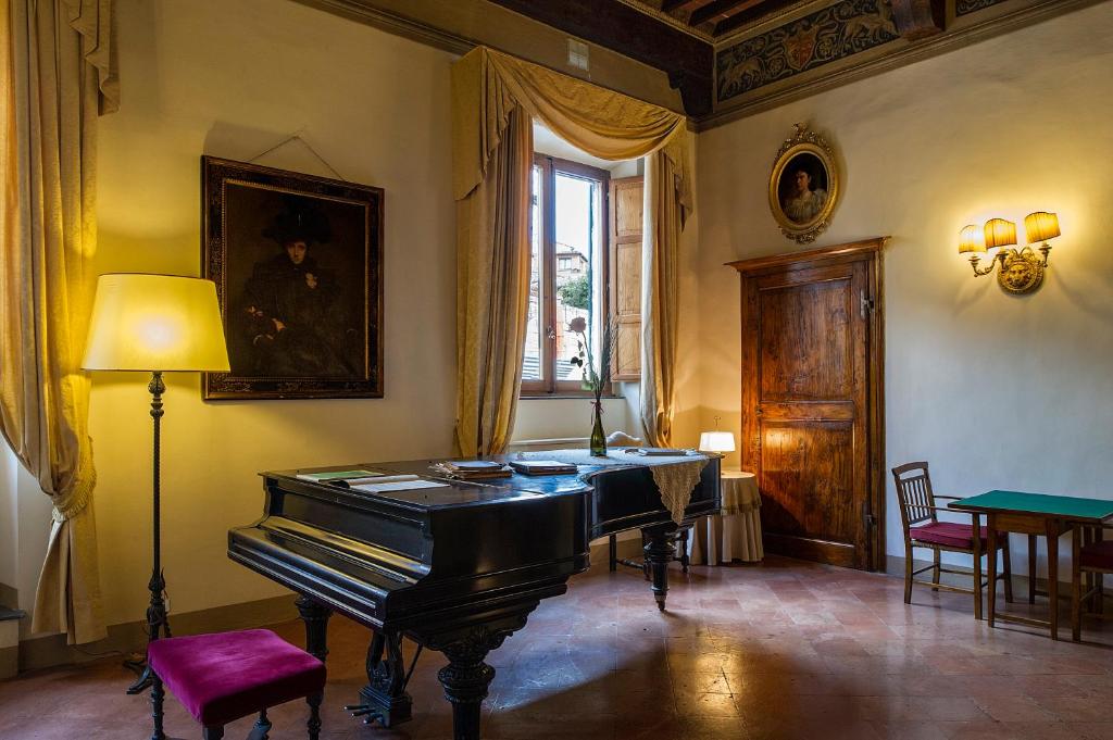 锡耶纳拉维佐宫酒店的客房设有钢琴、桌子和窗户。