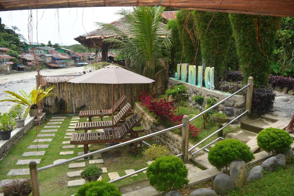 武吉拉旺武吉拉旺朱尼亚旅馆的一个带椅子、遮阳伞和冲浪板的花园