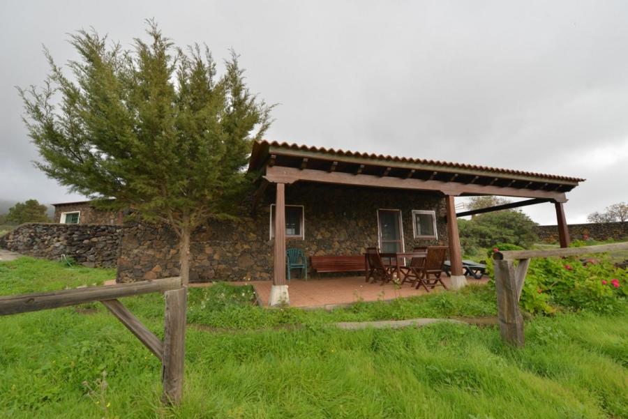 El Pinar del HierroCasa Rural El Pajar的石头房子,设有门廊和木栅栏
