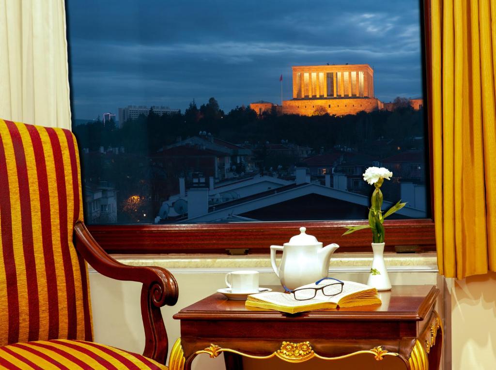 安卡拉怡凯乐酒店的窗户上带花瓶和玻璃杯的桌子