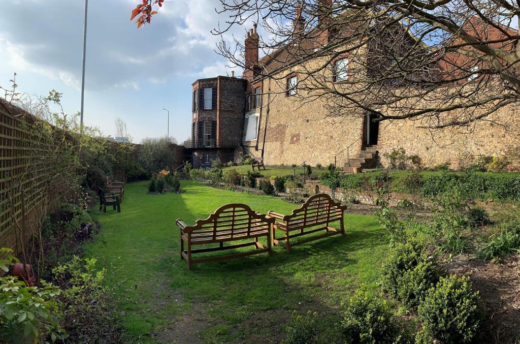坎特伯雷城堡别墅酒店亚的两把长椅坐在建筑物前面的草上