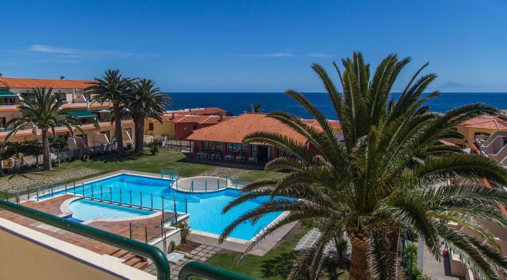 洛思坎加约斯AstroSunrise的一个带游泳池和棕榈树的度假村